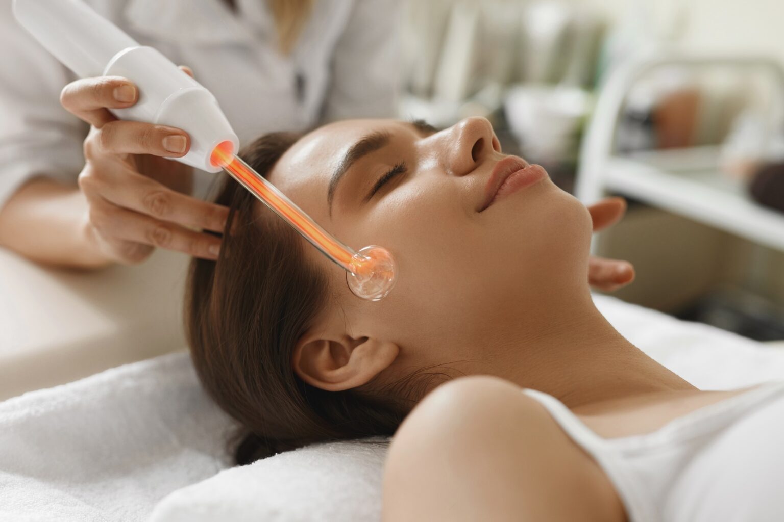 Woman receiving a facial treatment with a handheld device in a spa setting